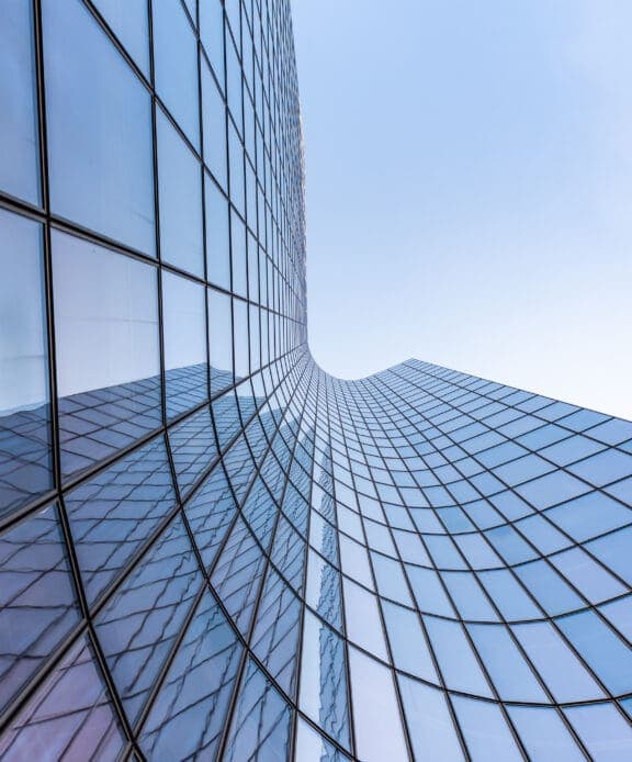 Blue curved glass skyscraper facade against sky